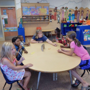 Woman and kids seated around a table.